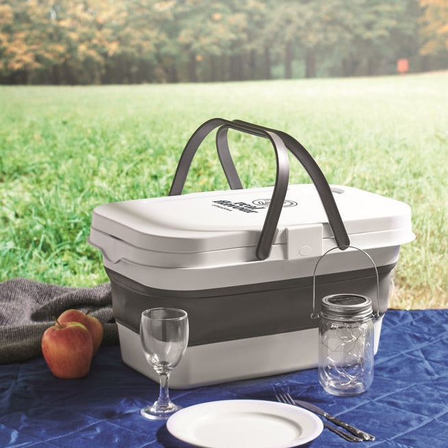 Picnic basket with tableware on a blue blanket outdoors
