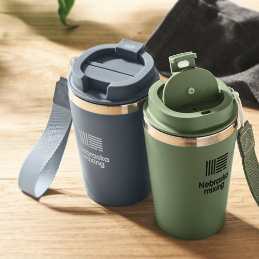 Two insulated travel mugs, one blue and one green, with Nebraska Mugs branding on a wooden surface.