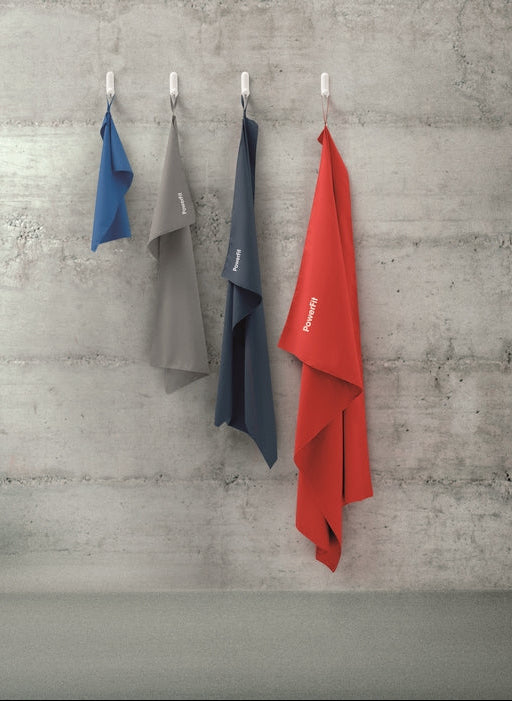Four colorful towels hanging on hooks against a concrete wall.