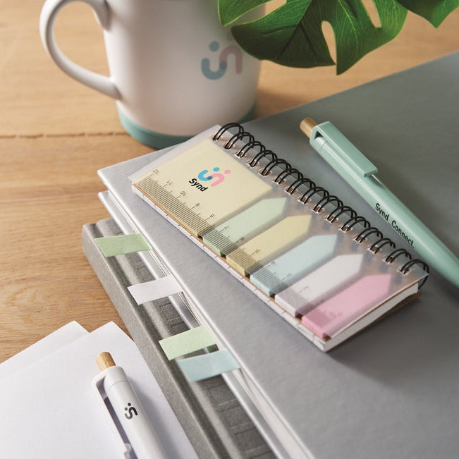 Notebook with colorful sticky notes, pen, and mug on a wooden surface