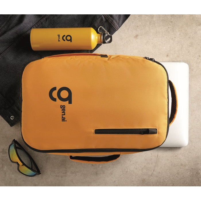 A bright yellow-orange Gen.ai branded backpack with black trim, shown in a styled flat-lay arrangement alongside a matching yellow water bottle, sunglasses, and a closed laptop on a textured concrete surface.