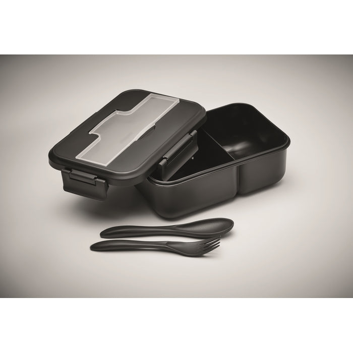 Black lunch box with compartments and utensils on a gray background