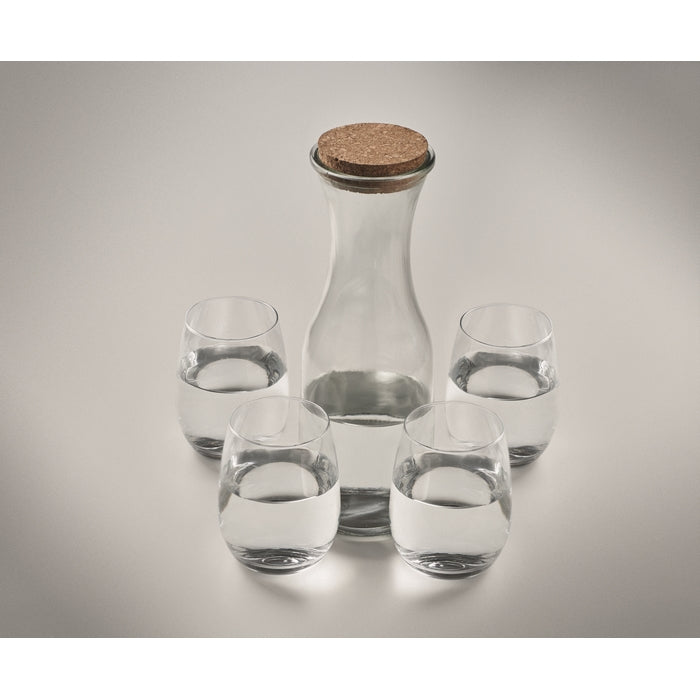 Clear glass carafe with cork lid and four matching glasses on a light gray background
