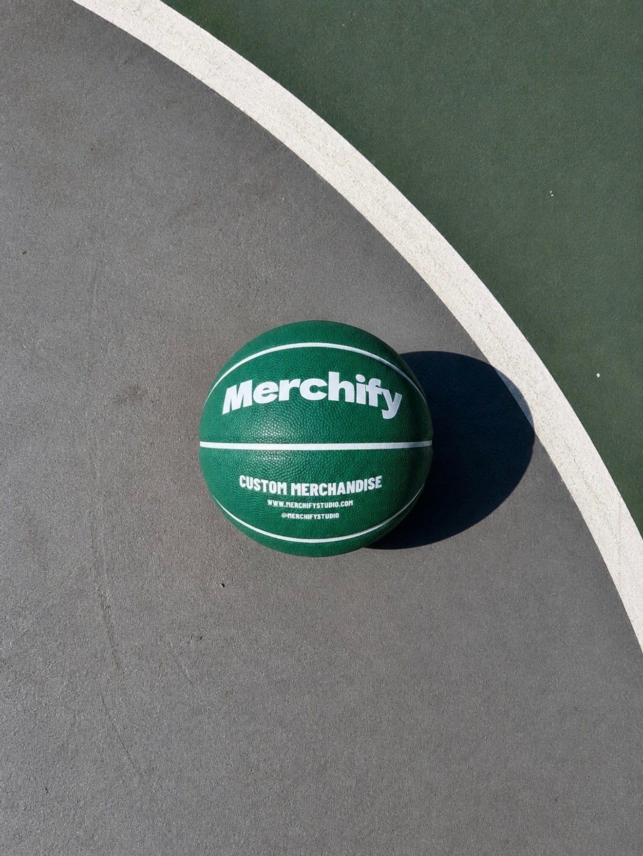 Custom branded basketball with Merchify logo on an outdoor basketball court