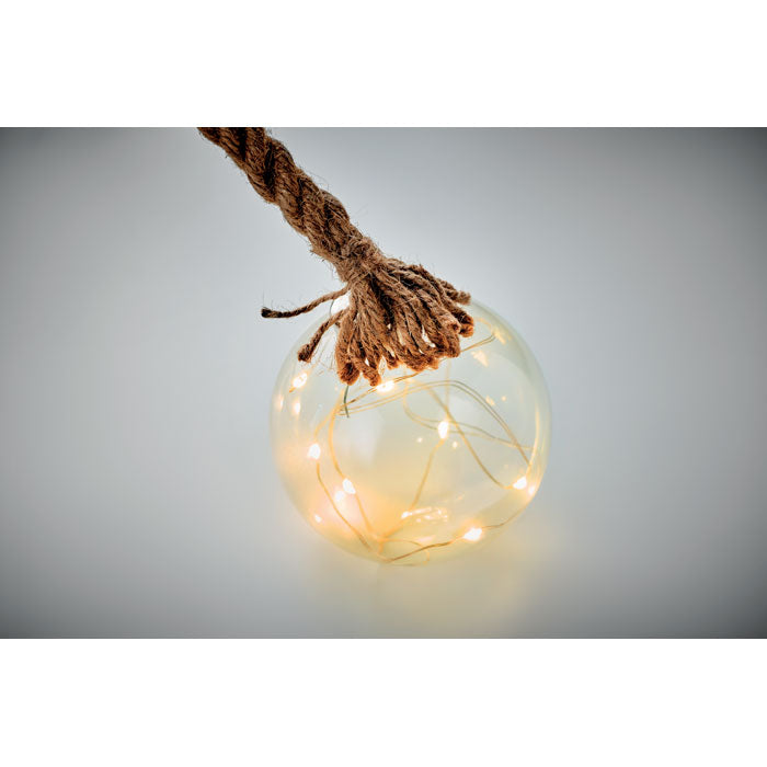 Glass christmas bauble with string lights hanging by a rope on a gray background